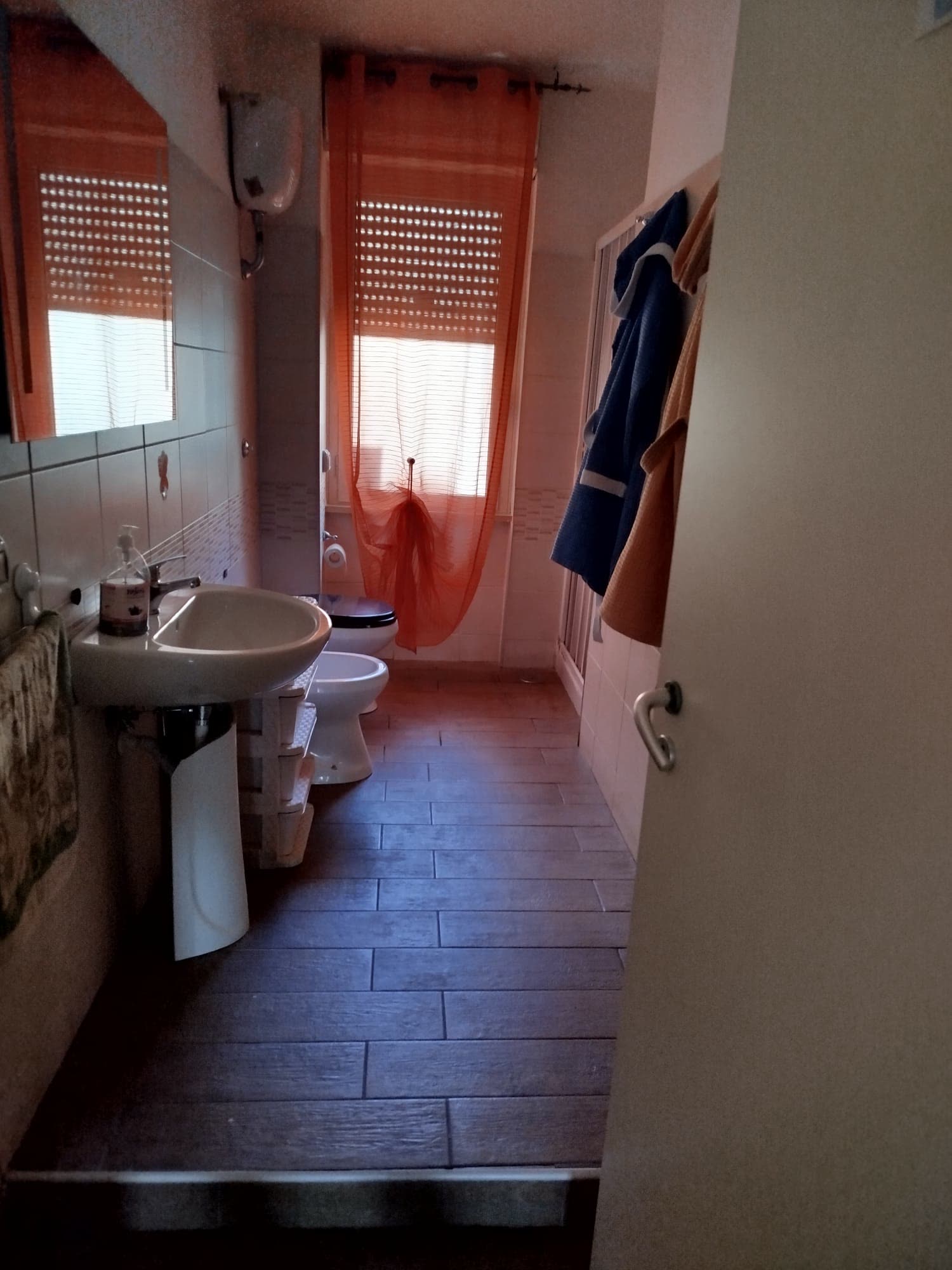 Bagno con doccia e tende arancioni nella comunità Costruttivamente