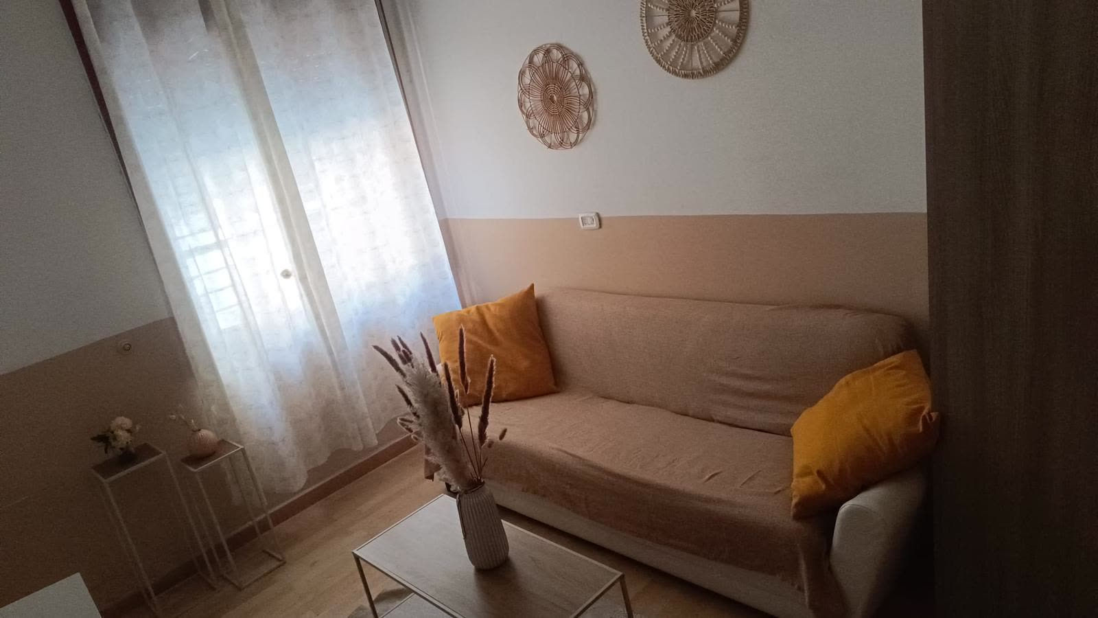 Angolo salotto con divano beige e cuscini senape nella comunità La Casa di Francesco